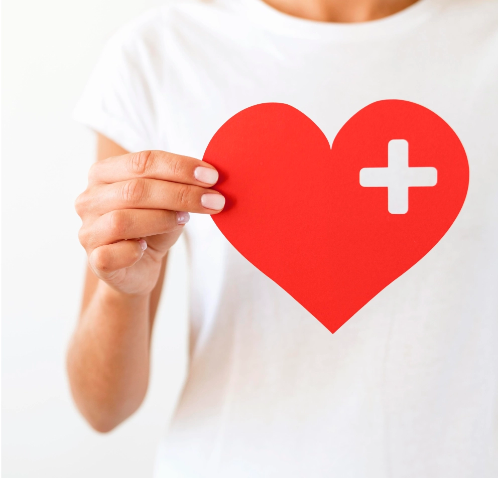 Persona tiene in mano un cuore di carta con una piccola croce per evidenziare l'importanza del corso di primo soccorso.