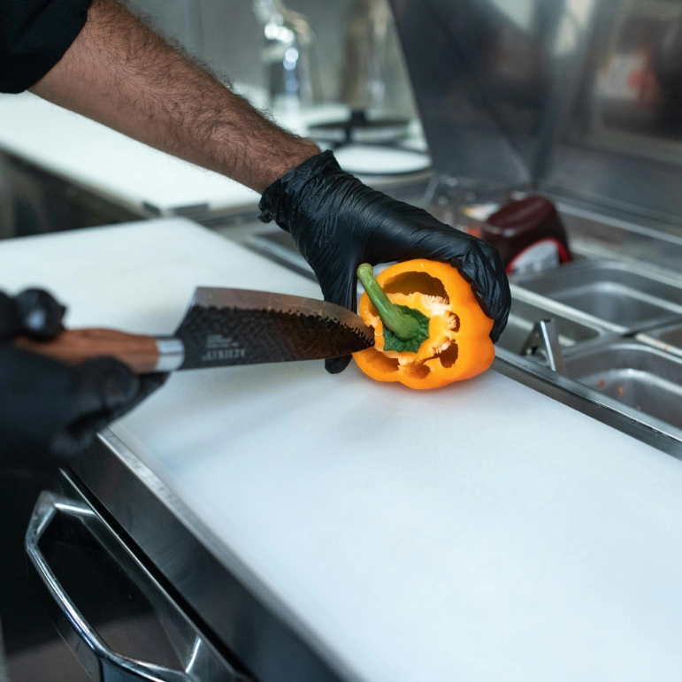 Preparazione alimenti con coltello in cucina professionale rappresentante i rischi concreti che vengono analizzati per la redazione di un DVR per Ristoranti a Cagliari